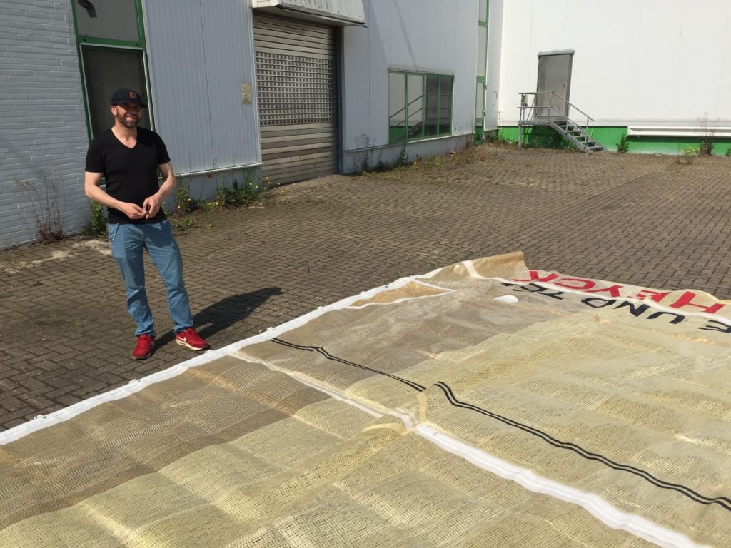 Mann steht neben der ausgelegten Plane auf dem Hof